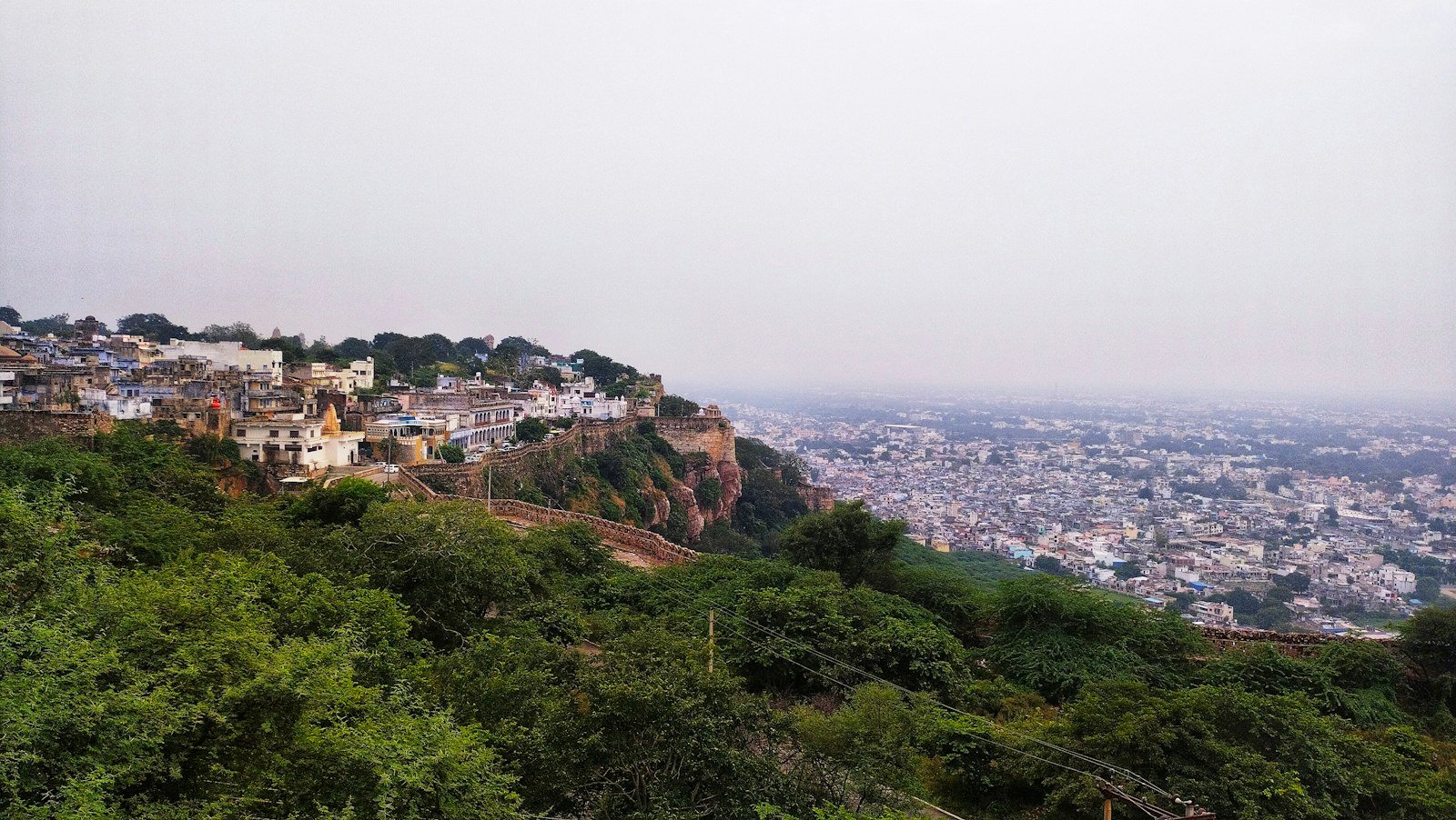 Hilltop buildings and fort walls above Chittorgarh city in hazy light