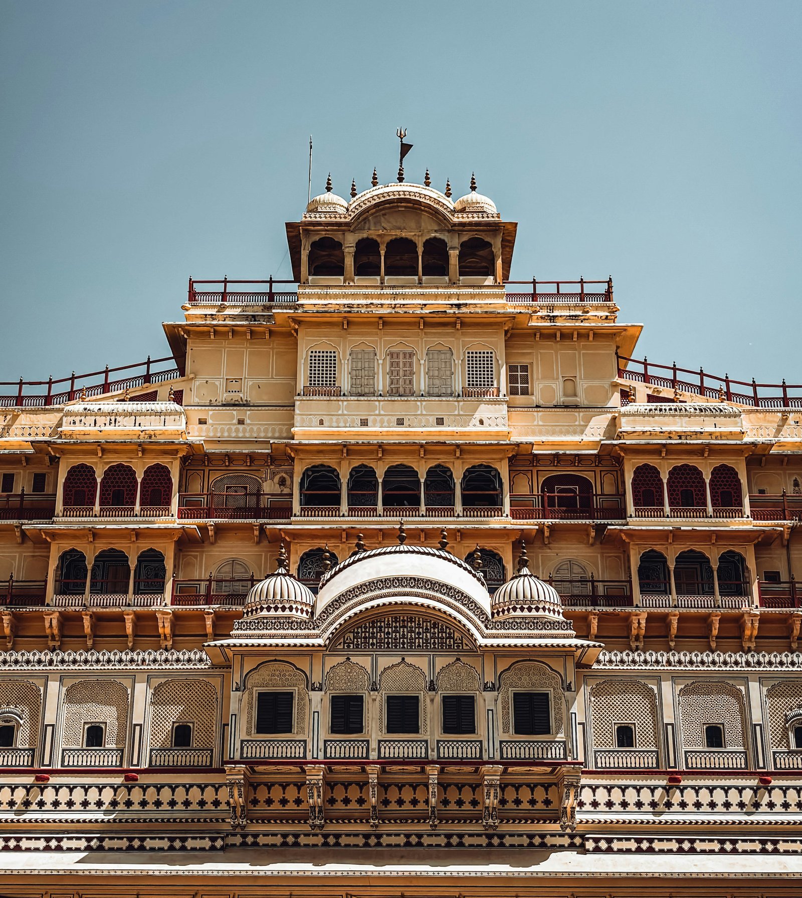 Ornate yellow City Palace façade in Jaipur with balconies and patterned white details.
