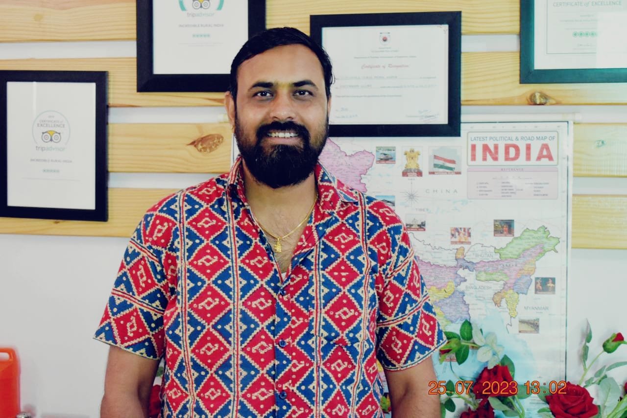 Rajendra Sharma in his travel office beside a map of India