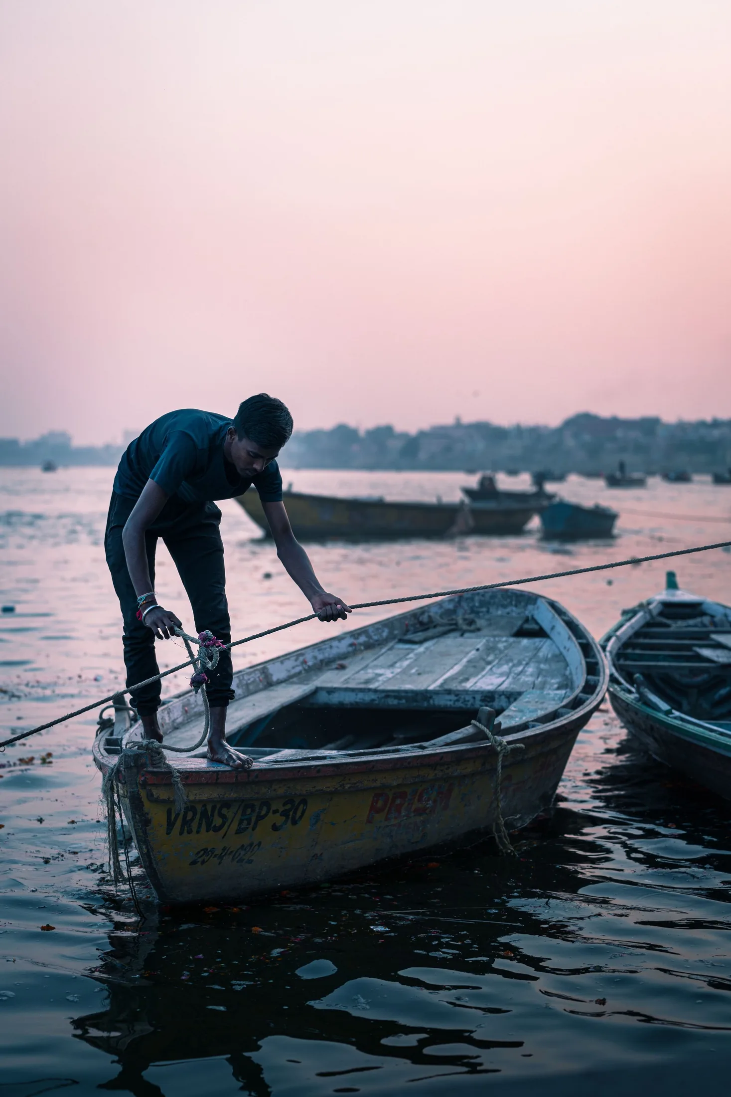 Boatman preparing a wooden boat at dawn in Varanasi